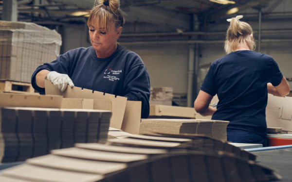 Two female workers stacking cardboard packaging dividers at the McLaren factory